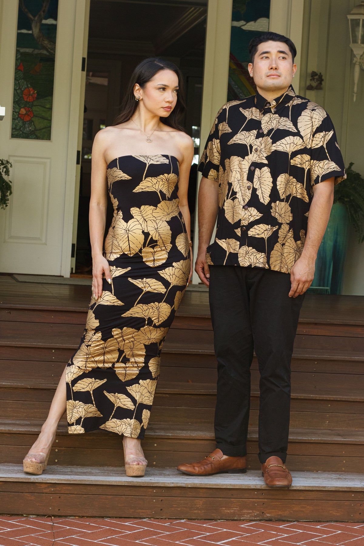 Men's Aloha Shirt in Black Gold Lauloa Keʻokeʻo Kalo — On-Model, with the Dress Leimakamae, on the steps | Kahulaleʻa